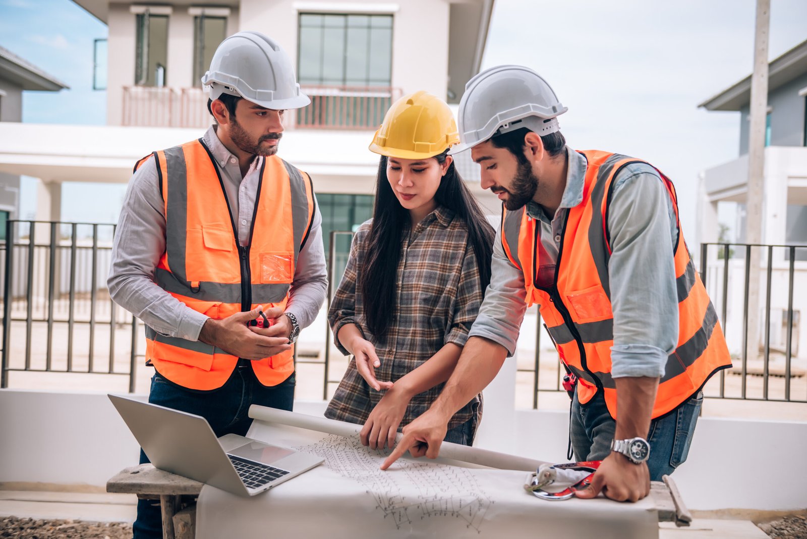 Civil engineer , Construction worker and Architects wearing hardhats and safety vests are working together at construction site ,building ,home in cooperation teamwork concept.